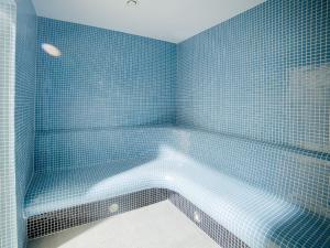 a blue tiled bathroom with a bath tub at DWIE SOSNY Apartament 52 in Ustronie Morskie