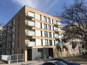 un edificio de apartamentos con coches estacionados frente a él en Barson Apartments, en Varsovia