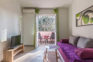 ein Wohnzimmer mit einem lila Sofa und einem TV in der Unterkunft Apartment Buic in Pula