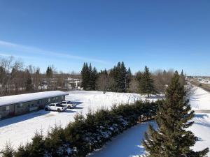 a snow covered parking lot with a christmas tree at New Country Motel in Swan River +3 photos