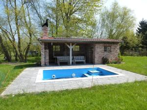 a small house with a blue pool in a yard at Traumhaftes Luxus-Ferienhaus in Warnkenhagen