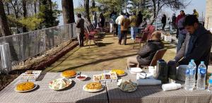 a man and woman sitting at a table with food at Pine Top Hotel Murree in Murree