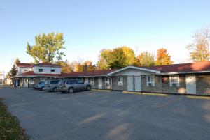 un estacionamiento con autos estacionados frente a un edificio en Kings Inn Orillia, en Orillia