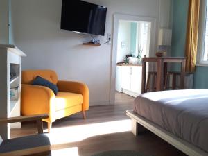 Un dormitorio con un sofá y un televisor en la pared. en Le Coquet, en Saint-Omer