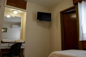 a hotel room with a bed and a television on the wall at Hotel Menossi in Río Cuarto