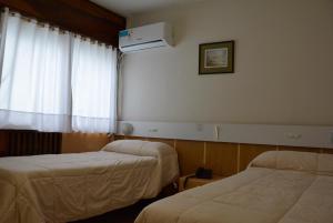 una camera d'albergo con due letti e una finestra di Hotel Menossi a Río Cuarto
