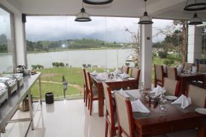 a restaurant with tables and chairs and a view of the water at Royal Lake Hotel in Nuwara Eliya
