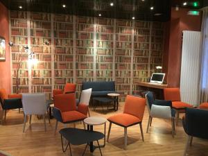 a waiting room with chairs and a wall of books at Hôtel Roc de Massabielle in Lourdes