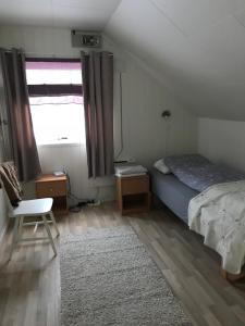 a bedroom with a bed and a chair and a window at Kjelkebakken Gard in Lyngseidet