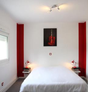 - une chambre avec un lit blanc et des murs rouges dans l'établissement Hotel de la Gare, à Saint-Mihiel