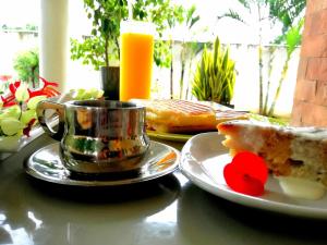 a table with a plate of food and a cup of orange juice at Bahama Breeze Beach Apartment in Cap Malheureux