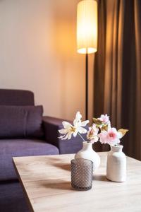 two white vases with flowers on a table at Daxburg Apartments in Innsbruck