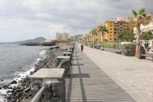 a person walking down a boardwalk next to the ocean at vacaciones frente al mar in Candelaria