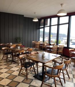 a restaurant with wooden tables and chairs and windows at Dalewood Inn in Port McNeill