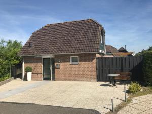 a brick house with a black fence and a bench at Moerellahof, Gezin & Familie vakantiehuis aan het Veersemeer ALLEEN GEZINNEN in Wolphaartsdijk