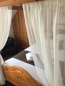 Woodthorpe Hotel في سكيجنيس: غرفة نوم بسرير مع ستائر بيضاء