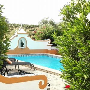 a swimming pool with two benches next to some bushes at Monte dos Aroeirais in Fronteira