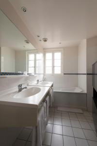 ein Badezimmer mit 2 Waschbecken und einer Badewanne in der Unterkunft Auberge de la Commanderie in Saint-Émilion