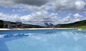 a group of chairs sitting next to a swimming pool at Gîtes Le Relais de Roquefereau in Penne-dʼAgenais