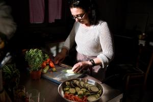 una mujer cortando verduras en una tabla de cortar en Madalenas B&B en Pelekas