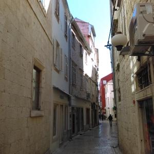 an alley with buildings and a person walking down the street at Apartment D2 4U in Zadar