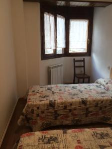 a bedroom with two beds and a chair and two windows at Apartamento Santa Marina in Tramacastilla de Tena