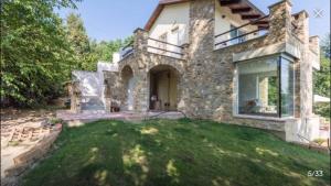 ein großes Steinhaus mit einem Rasenhof in der Unterkunft Piscina e relax nelle Langhe Villa Gaia in Bra