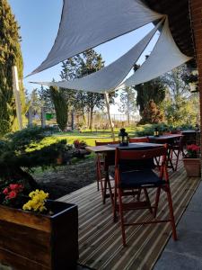 eine Holzterrasse mit Tischen und einem weißen Regenschirm in der Unterkunft Allevamento B&B in Pozzolgroppo