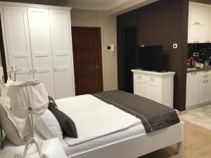 sypialnia z białym łóżkiem i telewizorem w obiekcie Lux new white apartment w Nowym Sadzie