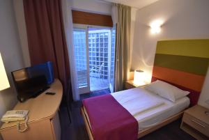 a hotel room with a bed and a desk with a television at Hotel Hecco in Sarajevo