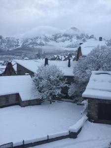 a house covered in snow with mountains in the background at Apartamento Santa Marina in Tramacastilla de Tena