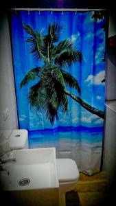 a bathroom with a shower curtain with a palm tree at SURFtoLIVE House in Somo