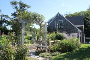 un jardin avec une pergola en face d'une maison dans l'établissement Lavender Bay, à Barnstable