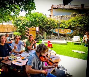 Un groupe de personnes assises autour d'une table avec un violon dans l'établissement SURFtoLIVE House, à Somo