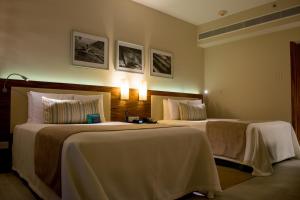 two beds in a hotel room with white sheets at Emporio Cancun - Buy All Inclusive Option in Cancún