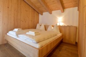 łóżko w drewnianym pokoju z ręcznikami w obiekcie Hotel St. Florian - Kaprun w Kaprunie