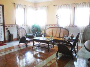 a living room with a table and chairs and windows at Hostal Alameda in Mérida
