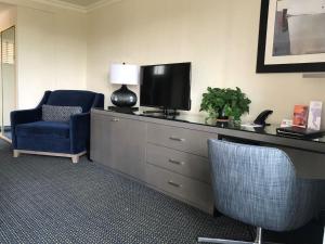 a room with a dresser with a tv and a chair at West Beach Inn, a Coast Hotel in Santa Barbara