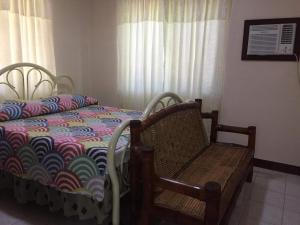 a bedroom with a bed and a chair and curtains at Home Style Accommodations in Botolan