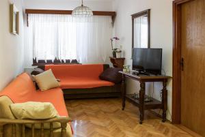 a living room with an orange couch and a television at Apartments Marijana in Senj