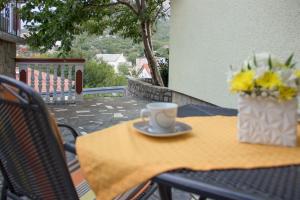 eine Tasse Kaffee auf einem Tisch mit einer Blumenvase in der Unterkunft Apartments Marijana in Senj