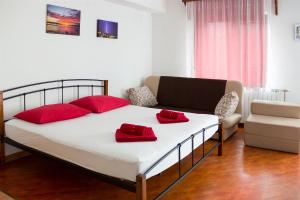 ein Bett mit roten Kissen und ein Sofa in einem Zimmer in der Unterkunft Apartments Marijana in Senj