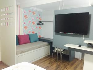 a small room with a couch with a tv on the wall at Hotel do Lago in Toledo