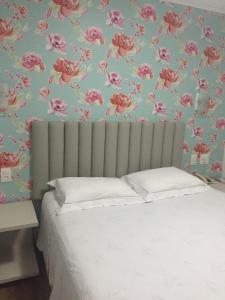 um quarto com uma cama com flores cor-de-rosa na parede em Hotel do Lago em Toledo