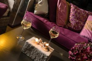 two glasses of wine on a table next to a couch at La Place Boutique Hotel in Antibes