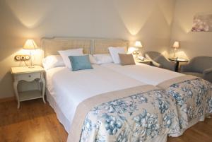a bedroom with a large white bed and two chairs at Hotel Villa Monter in Alcañiz