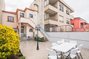 a patio with a white table and chairs in front of a building at À Francos Painting Artist 2 in Porto