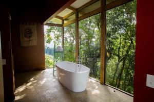 a bath tub in a room with a large window at Chayote Lodge in Zarcero