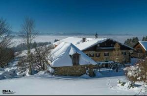 een huis bedekt met sneeuw voor een gebouw bij Bauernhof Moadl in Weyregg
