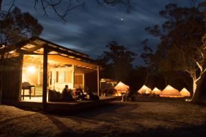 un grupo de personas sentadas fuera de una casa por la noche en Bay of Fires Bush Retreat en Binalong Bay